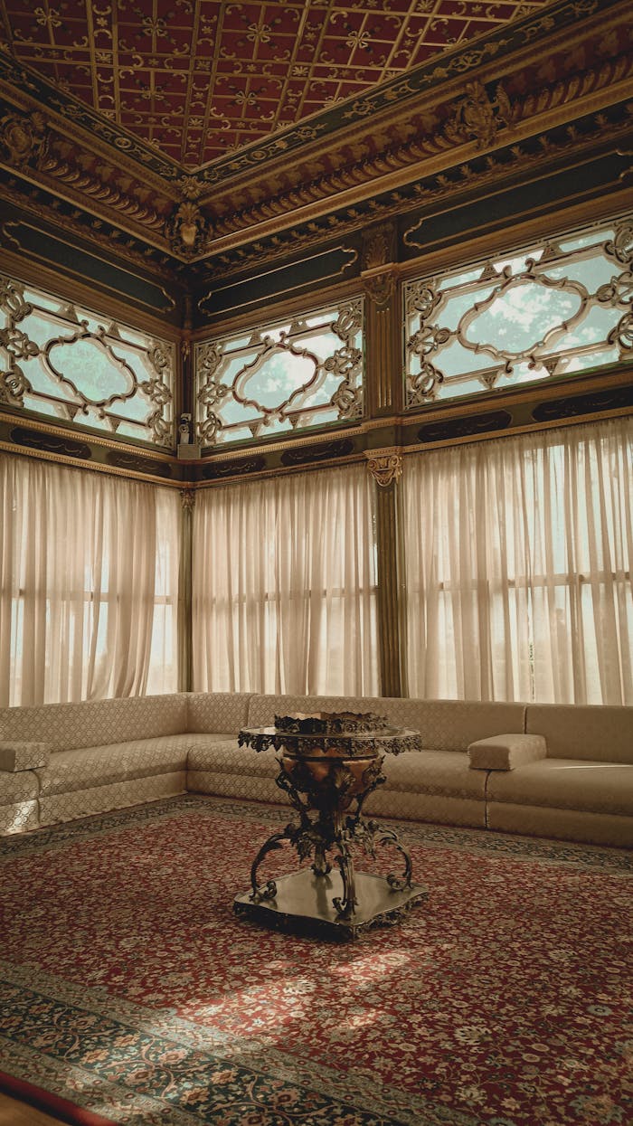 A lavish vintage room with ornate ceiling, stained glass, and elegant furniture.